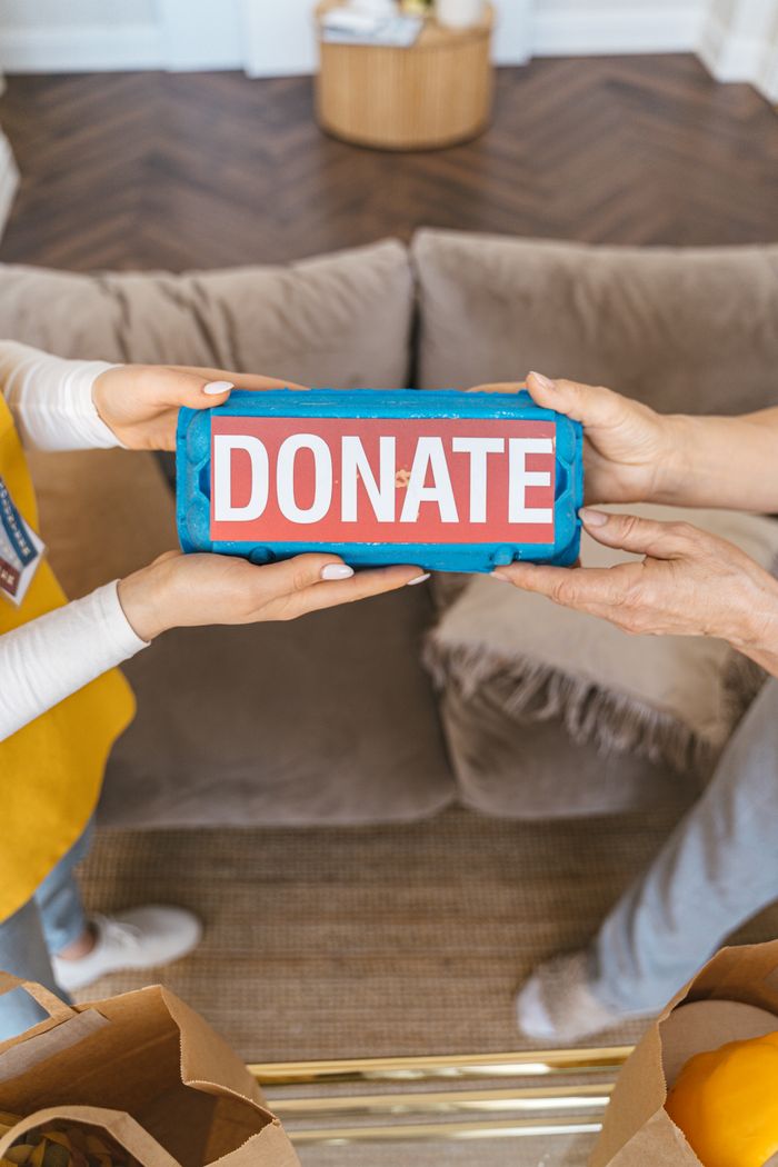 Two people exchanging a donation box indoors, symbolizing generosity and charity.