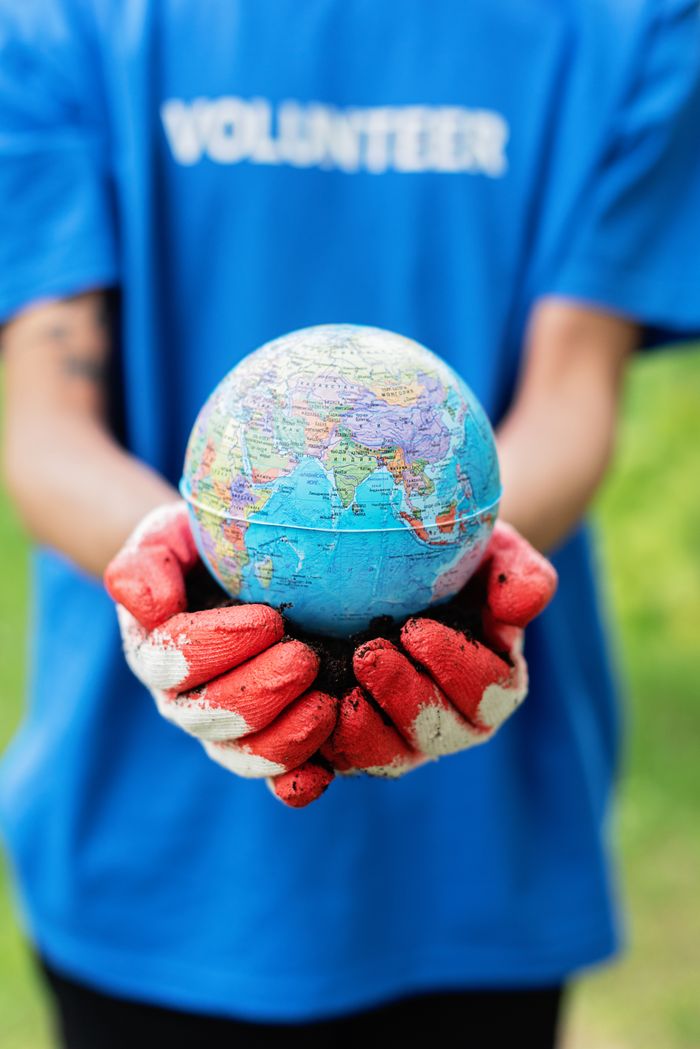 Close-up of hands holding a globe, symbolizing global environmental awareness and volunteering.